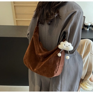 Detail of a large brown suede hobo bag with a soft cloud charm on a wide shoulder strap