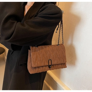Detail of dark caramel quilted suede shoulder bag with black metal chain strap and U-clasp