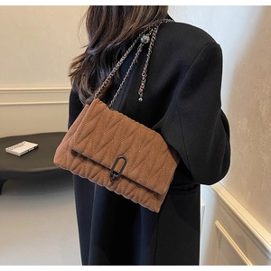Close-up of brown quilted PU leather crossbody bag with vintage metal chain strap