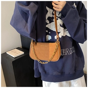 Detail view of brown faux crocodile leather bag with gold chain strap and brand lettering