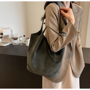 Detail view of the deep green suede tote bag showing texture and slim shoulder straps
