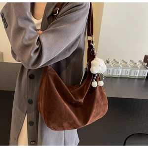 Detailed texture of brown suede shoulder bag with a cute white cloud plush pendant