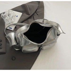 Close-up of Y2K silver metallic PU bag with dual front zipper pockets on a grey blazer
