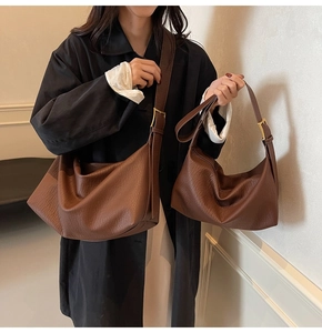 Gros plan de sacs hobo en cuir litchi marron avec boucles en métal doré mat