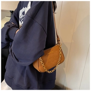 Detail of dark brown crocodile texture shoulder bag with gold chain and leather strap