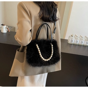 Detail of black plush crossbody bag featuring faux fur texture and elegant pearl chain accent