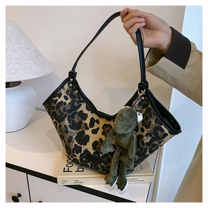 Gros plan détaillé d'un sac hobo à imprimé léopard avec un charmant pendentif grenouille