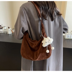 Brown hobo shoulder bag in faux suede with a cute white cloud charm in a cafe setting