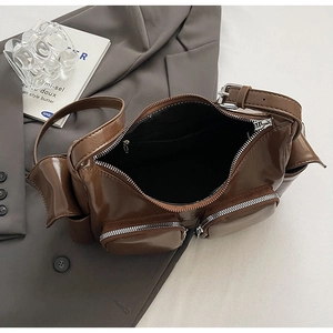 Detail of glossy brown PU leather shoulder bag with multi-pocket design and black inner lining