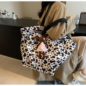 Detailed close-up of cow print tote bag with cute mouse pendant on model's shoulder
