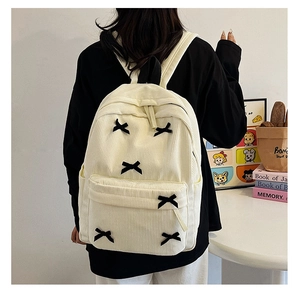 Détails d'un sac à dos en velours côtelé crème avec des nœuds noirs