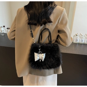 Detailed macro of black plush crossbody bag with silver bow charm and pearl accent