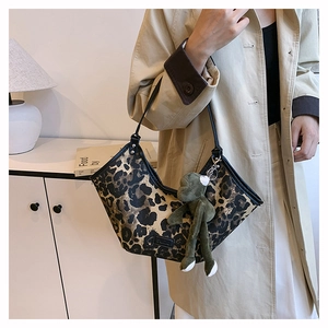 Détail du sac à main imprimé léopard avec une peluche grenouille verte sur un manteau beige