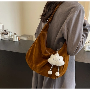 Detail of brown suede crescent bag with cute white cloud plush pendant accessory