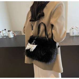 Detail of black faux fur handbag featuring silver bow pendant and adjustable leather strap