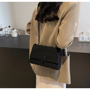 Close-up of black quilted PU leather crossbody bag with chain strap on a model