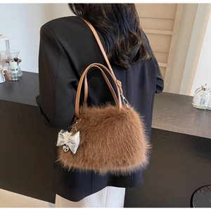 Detailed close-up of brown faux fur crossbody bag with pearl bow charm and leather straps