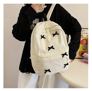 Détail d'un sac à dos en velours côtelé crème avec des nœuds noirs et poches latérales