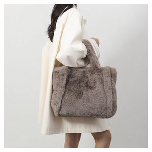 Gros plan d'un sac à main en fausse fourrure taupe porté par un mannequin en manteau
