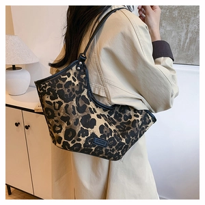 Détail du sac cabas à motif léopard avec lanières en cuir noir et logo de marque sur le côté