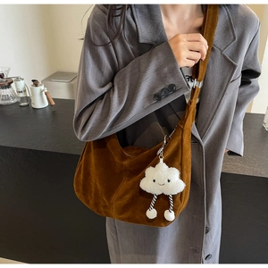 Caramel brown suede hobo bag with cloud plush charm shown on female model in a cafe