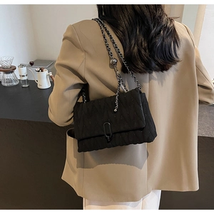 Close-up of a black quilted PU leather crossbody bag with adjustable silver chain strap