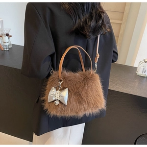 Detail of brown plush crossbody bag with leather handle and silver bow pearl pendant