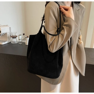 Minimalist black PU leather tote bag with cylindrical handles on model in cafe