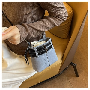 Dettaglio della borsa a secchiello opaca azzurra con lacci e cinture nere su outfit casual