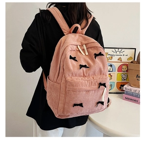 Sac à dos en velours côtelé rose avec détails nœuds noirs porté en vue arrière