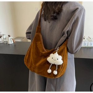 Detailed macro view of brown suede hobo bag with wide strap and cloud pendant charm