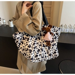 Close-up of canvas tote bag with cow print pattern and cute mouse plush pendant