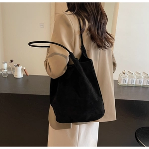 Minimalist black matte PU leather tote bag shown on shoulder in a lifestyle setting