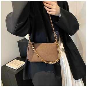 Brown crocodile pattern shoulder bag with gold chain worn by model in black blazer