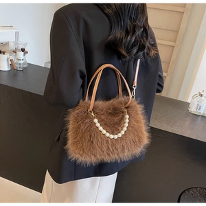 Close-up of brown plush faux fur handbag with elegant pearl handle and leather strap