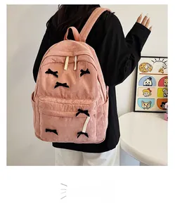 Sac à dos rose en velours côtelé avec nœuds noirs et grande poche avant zippée