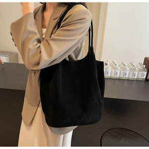 Detail of a black matte suede tote bag with slim shoulder straps for casual commute style