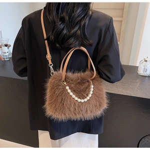 Detail of plush brown shoulder bag featuring luxury pearl chain and faux fur texture