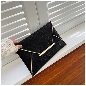 Détail d'une pochette de soirée à paillettes noires avec bordure en métal doré et fermoir