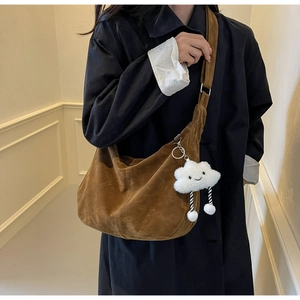 Detail of a dark brown suede hobo bag with wide strap and cute white cloud pendant