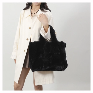 Grand sac à main en peluche noire porté par un mannequin pour un look d'hiver chic