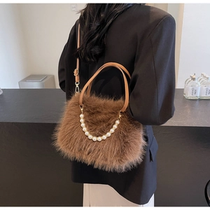 Brown plush crossbody bag with pearl handle and leather strap shown on a model