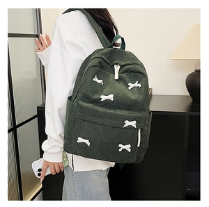 Détail d'un sac à dos en velours côtelé vert avec des nœuds blancs et des rayures