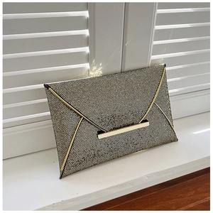 Détail d'une pochette de soirée dorée en tissu pailleté avec une bordure métallique en V