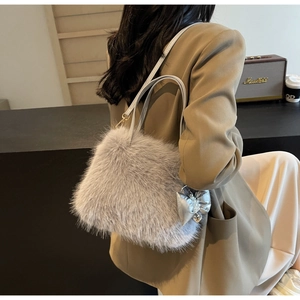 Detail of grey faux fur crossbody bag with silver bow charm on a stylish model