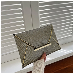 Détail de la pochette enveloppe scintillante noir et or avec garniture en métal en V