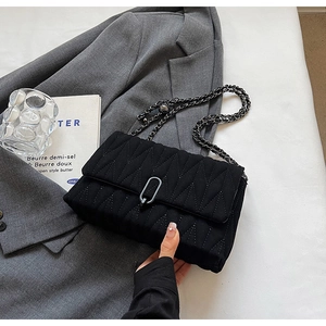 Minimalist black quilted PU leather shoulder bag with chain strap on a grey blazer