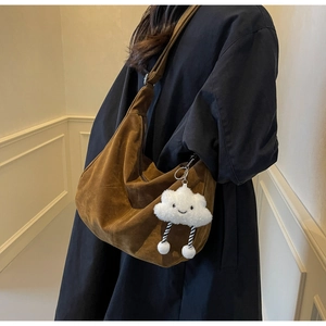 Detail of a dark brown PU leather hobo bag with a cute plush cloud charm and strap texture