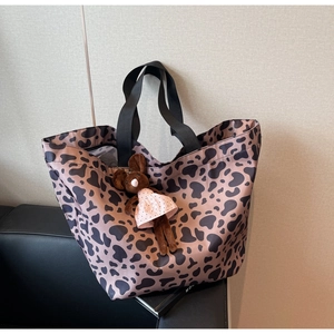 Fashionable leopard print tote bag with black straps and a cute mouse plush charm on a sofa