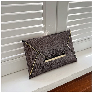 Détail d'une pochette enveloppe scintillante avec bordure dorée sur fond de persiennes